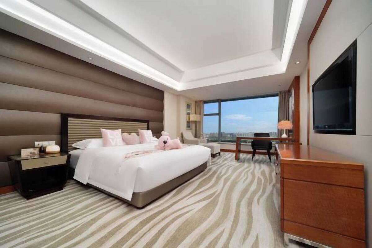 Una habitación de hotel moderna con una cama grande, un escritorio y un televisor.