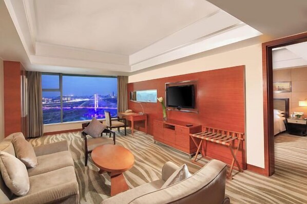 A hotel room with a large window, a television, a desk, and a seating area with a sofa and chairs. - GALAXY TIANFU HOTEL (Nanchong)