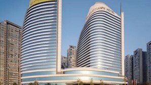 Dos hoteles modernos de líneas curvas y señalización que indica sus nombres.