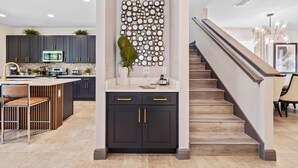Una cocina moderna con armarios oscuros, una isla central y un elemento decorativo en la pared.