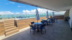 A rooftop terrace with outdoor seating, a pool, and a view of the city skyline. - Flat Térreo 02 Jardim by La Playa (Ipojuca)