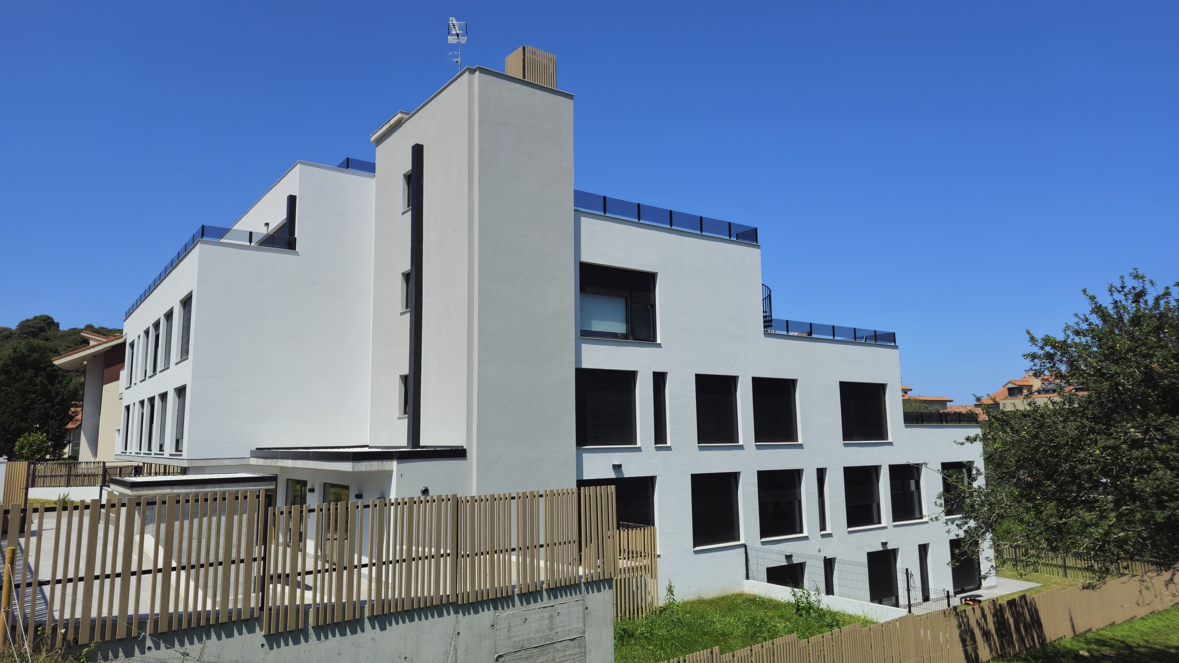 Un bâtiment moderne doté d’un toit plat, de grandes fenêtres et d’une clôture en bois à l’avant.