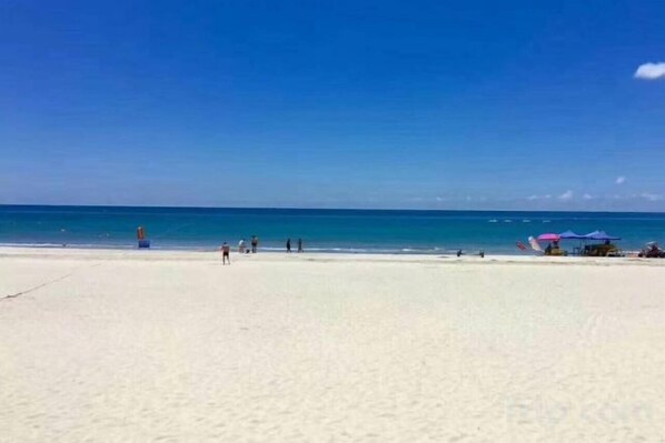 A beach with a clear sky, a sandy shore, and a few umbrellas. - Hilton Hotel (Taishan)