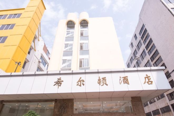 A hotel entrance with a sign in a foreign language, surrounded by modern buildings.