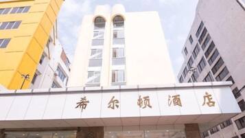 A hotel entrance with a sign in a foreign language, surrounded by modern buildings.