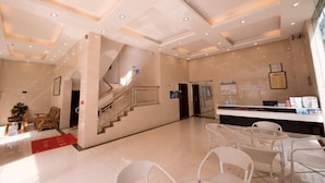 A hotel lobby with a reception desk, seating area, staircase, and a large window. - Hilton Hotel (Taishan)