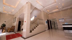 A spacious lobby with a staircase, a reception desk, and a red carpet. - Hilton Hotel (Taishan)