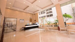A modern hotel lobby with a reception desk, seating area, and large windows offering views of the outside. - Hilton Hotel (Taishan)