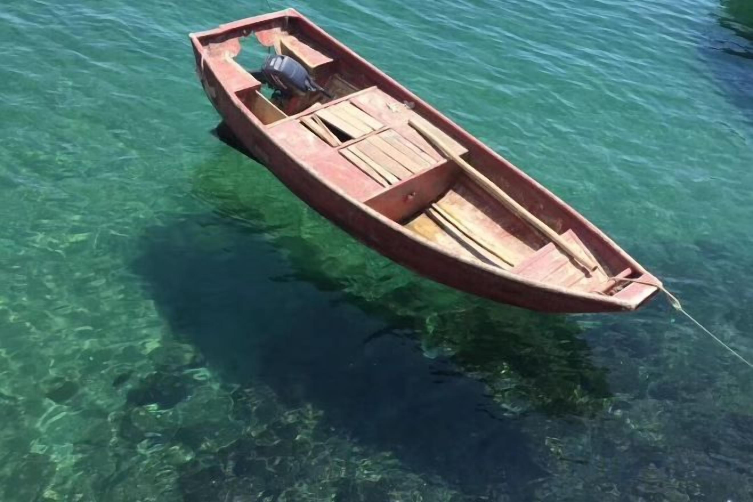 A small wooden boat floating on clear water.