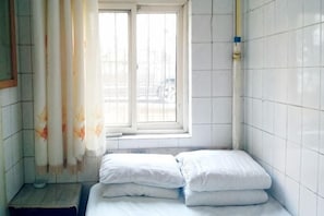 Ein kleines Badezimmer mit Fliesen, einem Fenster, einem Handtuchhalter und einer Toilette.