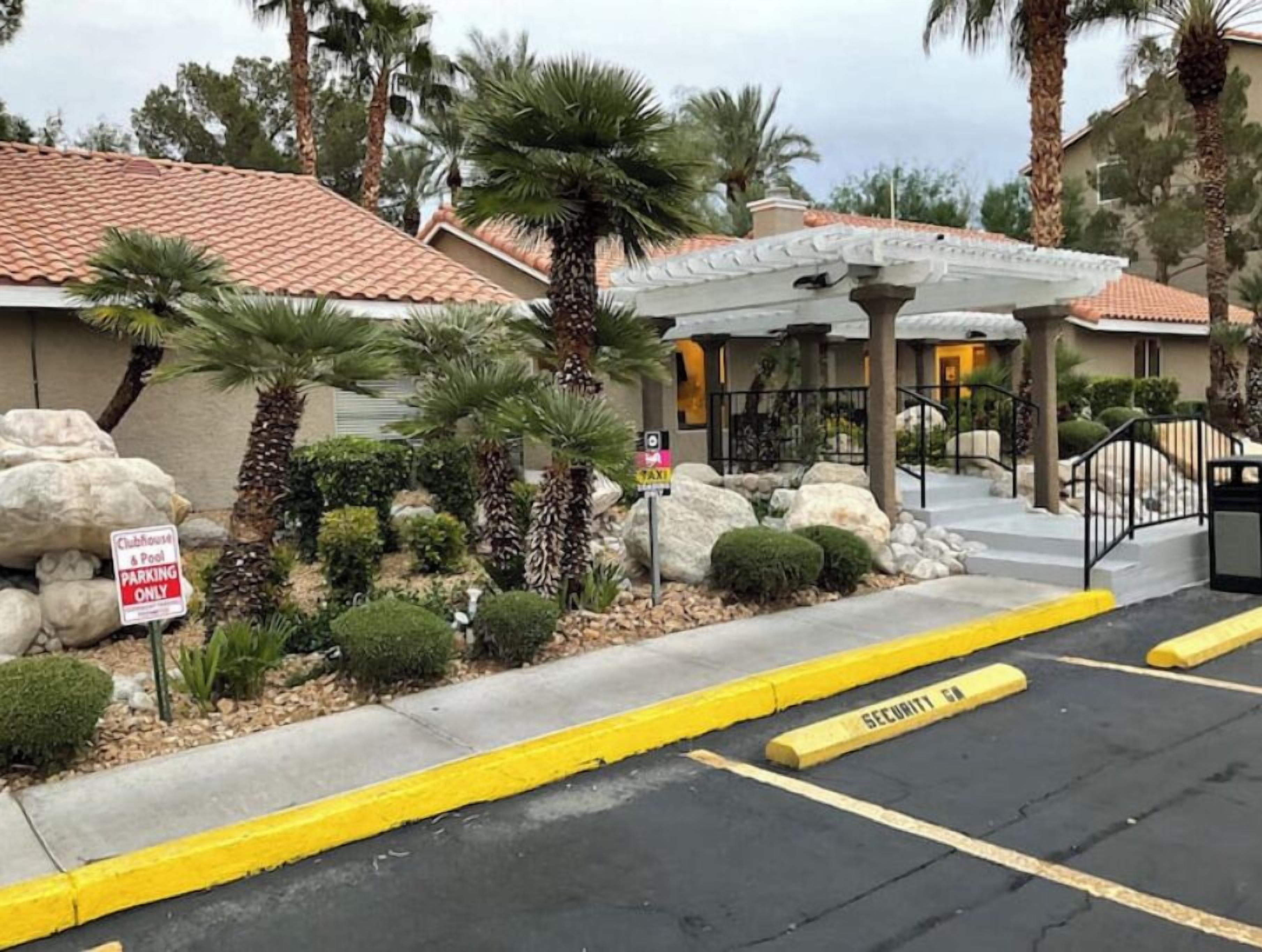 A hotel entrance with a covered patio, palm trees, and a 'Clubhouse & Pool Parking Only' sign.