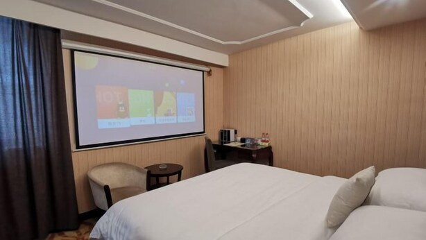 A hotel room with a bed, a desk, a chair, a projector screen, and a wooden wall. - Vienna Hotel (Guiyang Fountain Subway Station Yangmingci Subway Station) (Guiyang)