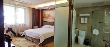 Una habitación de hotel con cama, escritorio, silla, ducha y baño.