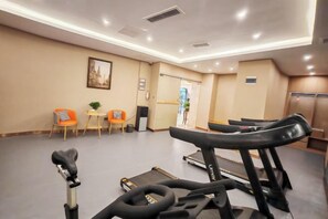 Una palestra con attrezzature per esercizi, una reception e un ingresso che dà su un'altra stanza.