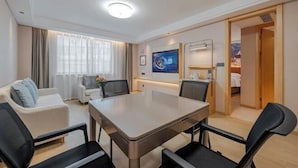 A hotel room with a dining table, two chairs, a sofa, a TV, and a bed. - Vienna Hotel (Guiyang Fountain Subway Station Yangmingci Subway Station) (Guiyang)
