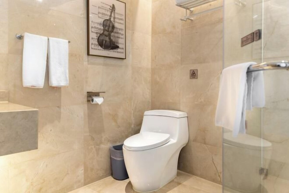 A modern bathroom with a toilet, a glass shower enclosure, and a marble floor.