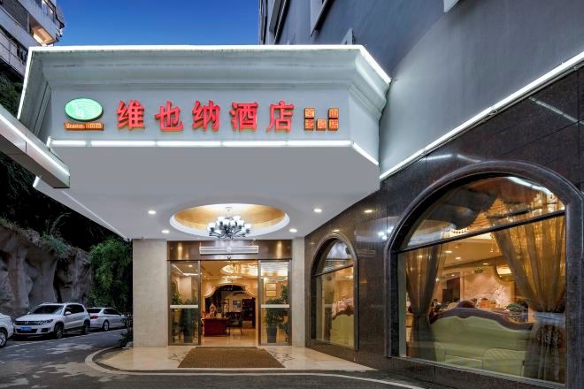 A hotel entrance with a sign, a reception desk, and a car parked outside.