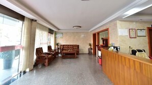 Un vestíbulo de hotel con mostrador de recepción, zona de estar y un amplio ventanal.