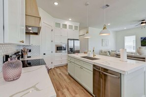 Una cocina moderna con armarios blancos, electrodomésticos de acero inoxidable y encimera de mármol.