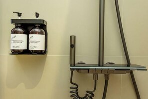 Un espace douche équipé d’un distributeur de savon mural et d’un pommeau de douche à main.