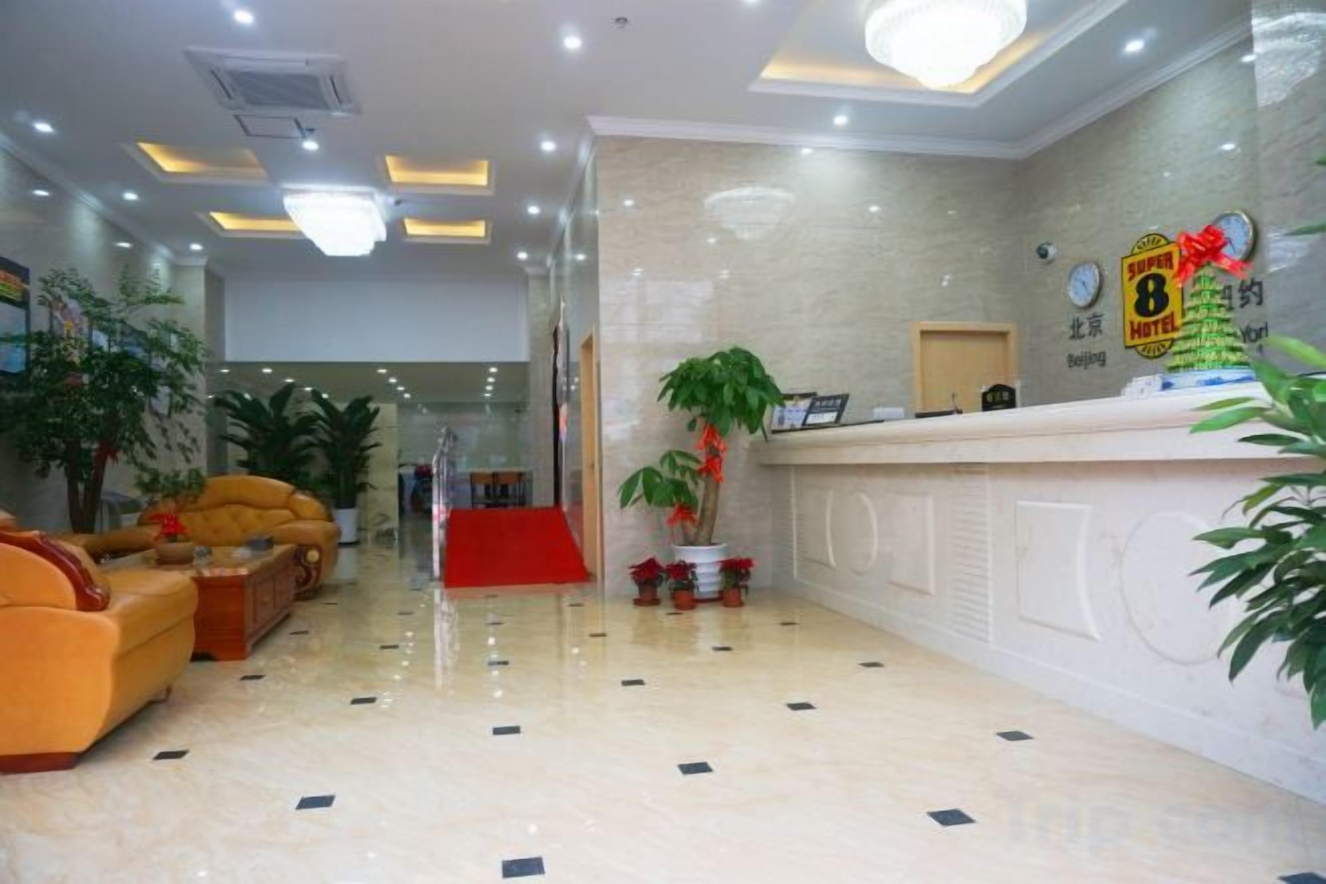 A hotel lobby with a reception desk, seating area, and potted plants.