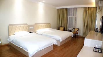 Quarto de hotel com duas camas, uma escrivaninha, uma cadeira e uma janela com cortinas.