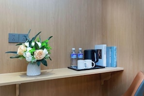 A wooden desk with a vase of flowers, a coffee maker, two bottles of water, and a tray with two cups. - Super 8 Shanghai Dongjing Huanlegu Dongye Road (Shanghai)