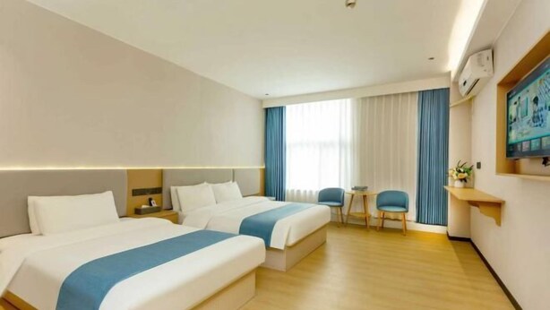 A hotel room with two beds, a small table, a chair, and a TV on the wall. - Super 8 Shanghai Dongjing Huanlegu Dongye Road (Shanghai)