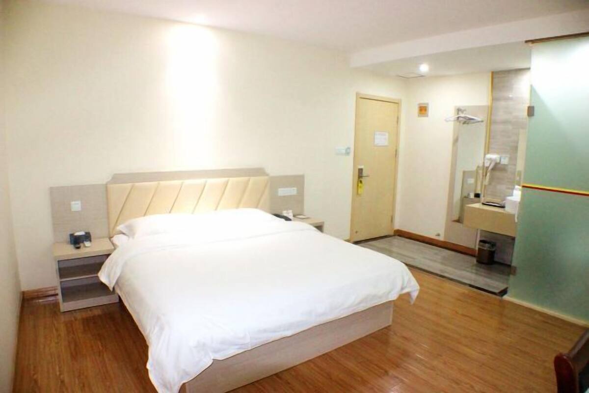 A hotel room with a bed, bedside table, and a mirror.