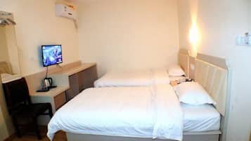 Quarto de hotel com uma cama, uma mesa com um computador e uma cadeira.