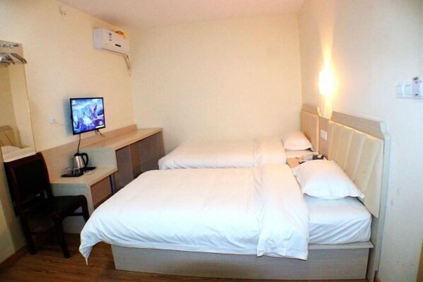 Ett hotellrum med en säng, ett skrivbord med en dator och en stol.
