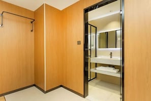 A wooden-walled bathroom with a white sink and mirror, a towel rack, and a shower area. - Super 8 Shanghai Dongjing Huanlegu Dongye Road (Shanghai)