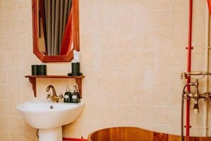 A bathroom with a white sink, wooden vanity, and a red pipe. - Ngoi Lang CO 77 Hoang Dieu (Dalat)