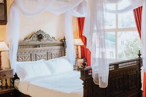 A bed with a canopy, a nightstand, a lamp, and a window with curtains. - Ngoi Lang CO 77 Hoang Dieu (Dalat)