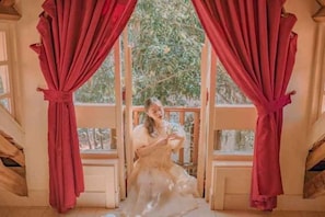 A room with a view through a window, curtains, and a wooden railing. - Ngoi Lang CO 77 Hoang Dieu (Dalat)