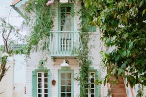 A two-story building with green shutters, a balcony, and hanging plants. - Ngoi Lang CO 77 Hoang Dieu (Dalat)