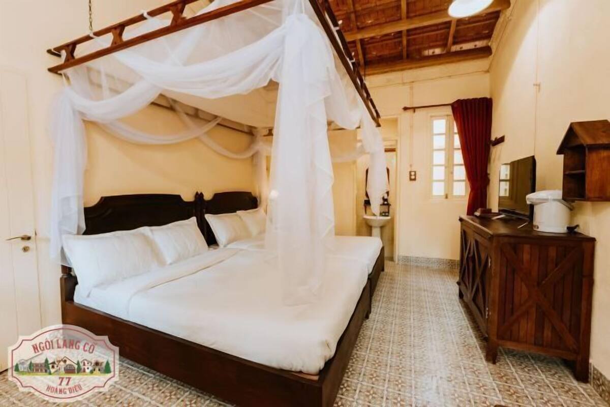 Un dormitorio con cama con dosel, cómoda de madera y suelo de baldosas.