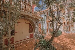 A courtyard with a large arched entrance, a tree, and a building with multiple windows and balconies. - Ngoi Lang CO 77 Hoang Dieu (Dalat)