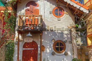 A building with a wooden balcony, a round window, and a door with a sign. - Ngoi Lang CO 77 Hoang Dieu (Dalat)
