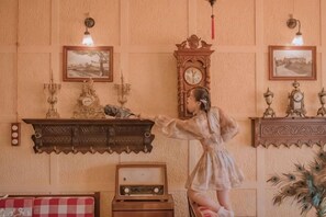 Une pièce au décor d’époque, avec un meuble en bois, une radio et une horloge au mur.