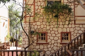 A building with a stone facade, a staircase, and a window with a clock. - Ngoi Lang CO 77 Hoang Dieu (Dalat)