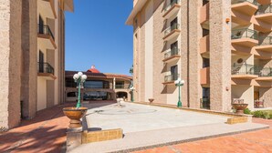 A courtyard with a fountain, a pool, and a building with multiple balconies.