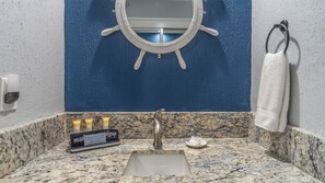 Ein Badezimmer mit Waschbecken, Spiegel und Pflegeprodukten.