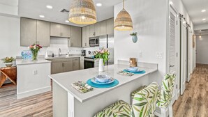 A modern kitchen with white cabinetry, a central island, and pendant lighting. - Resort Pool & Spa, Fitness Center, Pet Friendly, Waterfront Condo in Downtown! (Sarasota)