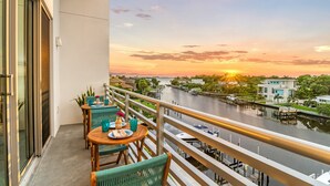 A balcony with a table set for two, overlooking a river with boats and buildings in the background. - Resort Pool & Spa, Fitness Center, Pet Friendly, Waterfront Condo in Downtown! (Sarasota)