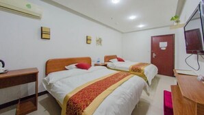 Habitación de hotel con dos camas, un escritorio, una silla, un televisor y aire acondicionado.