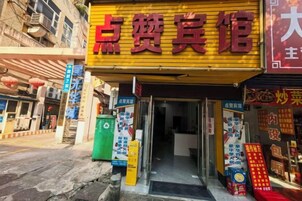 Fachada con un letrero amarillo, una entrada visible y varios anuncios.