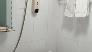 Un baño con inodoro, secamanos y una toalla colgada en la pared.