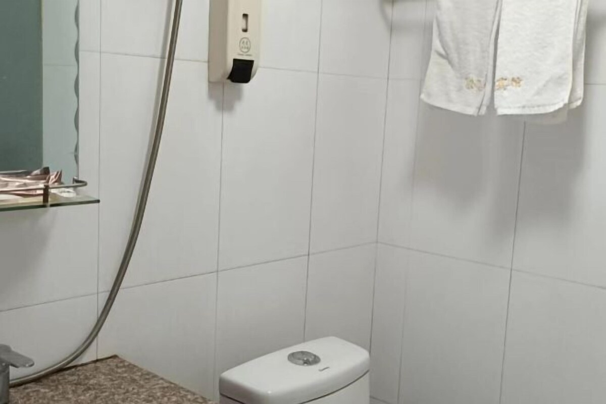 Une salle de bain équipée de toilettes, d’un sèche-mains et d’une serviette accrochée au mur.