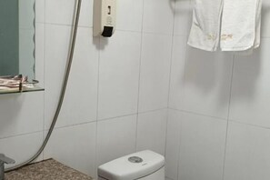 Une salle de bain équipée de toilettes, d’un sèche-mains et d’une serviette accrochée au mur.
